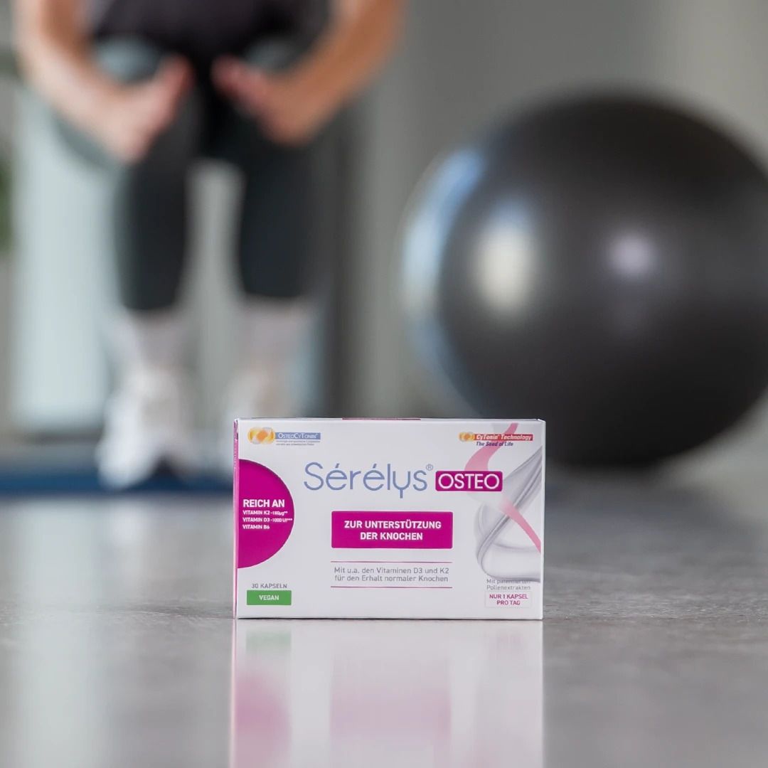 Boîte Sérélys OSTEO posée au sol. En arrière-plan, une personne et un ballon d'exercice.