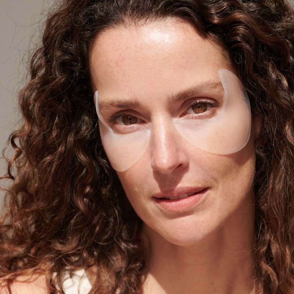 Femme portant des APRICOT Eye Temple Pads sur les yeux. Les coussinets sont transparents et couvrent le contour des yeux.