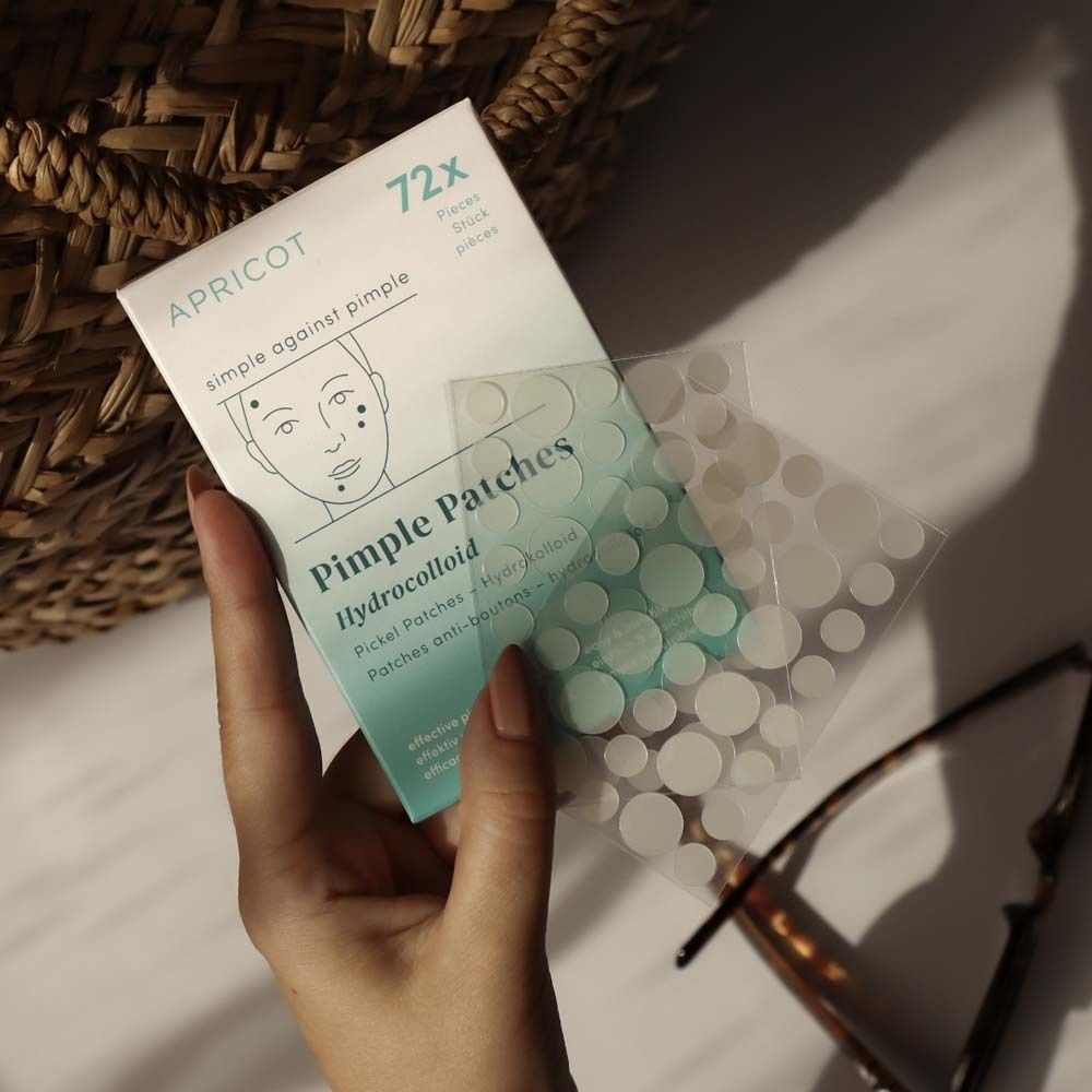 Main tenant une boîte de patchs anti-boutons. Marque APRICOT. 72 pièces. Patchs hydrocolloïdes.
