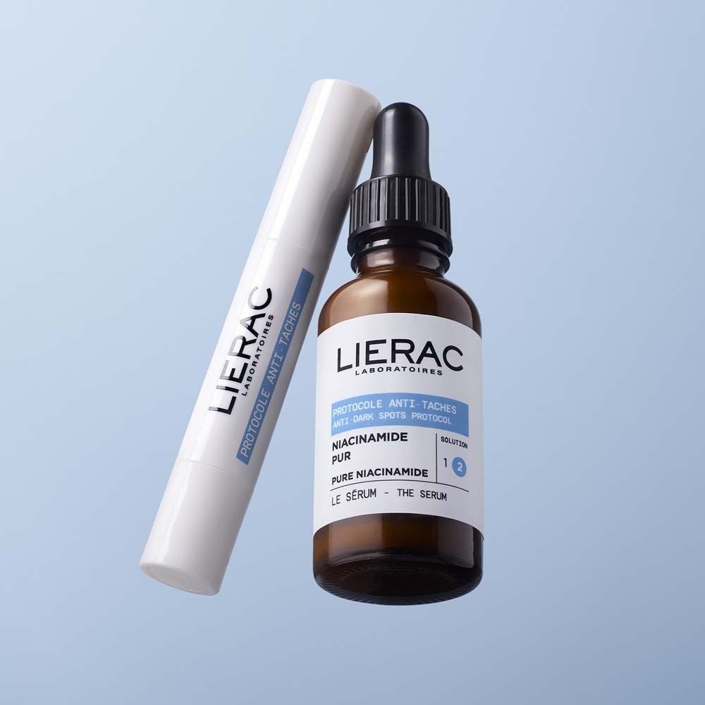 Stick blanc et flacon brun. Logo LIERAC et informations produit: Protocole Anti-Taches, Vitamine E, Le Stick Solution. Flacon de sérum.