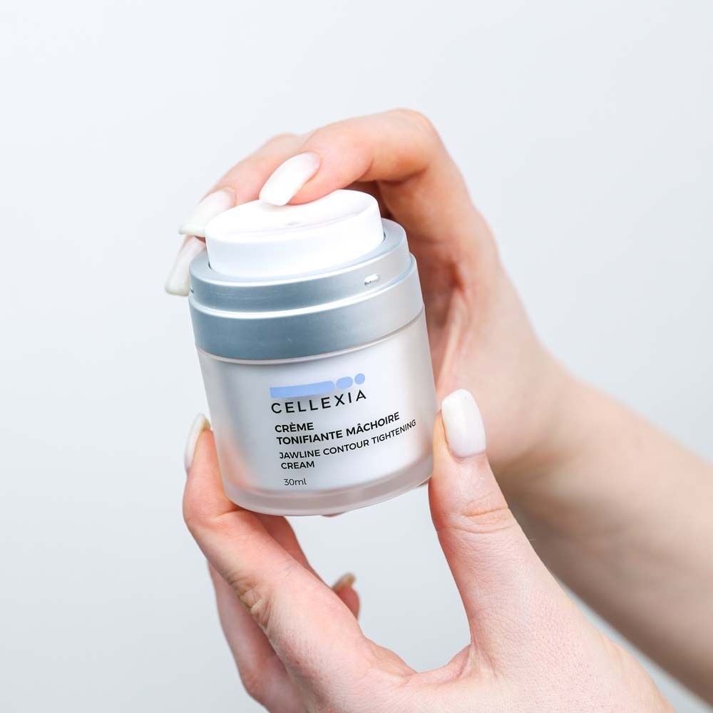 Hände halten einen Creme-Tiegel. Aufschrift: Cellexia, Crème Tonifiante Mâchoire, Jawline Contour Tightening Cream. 30ml.