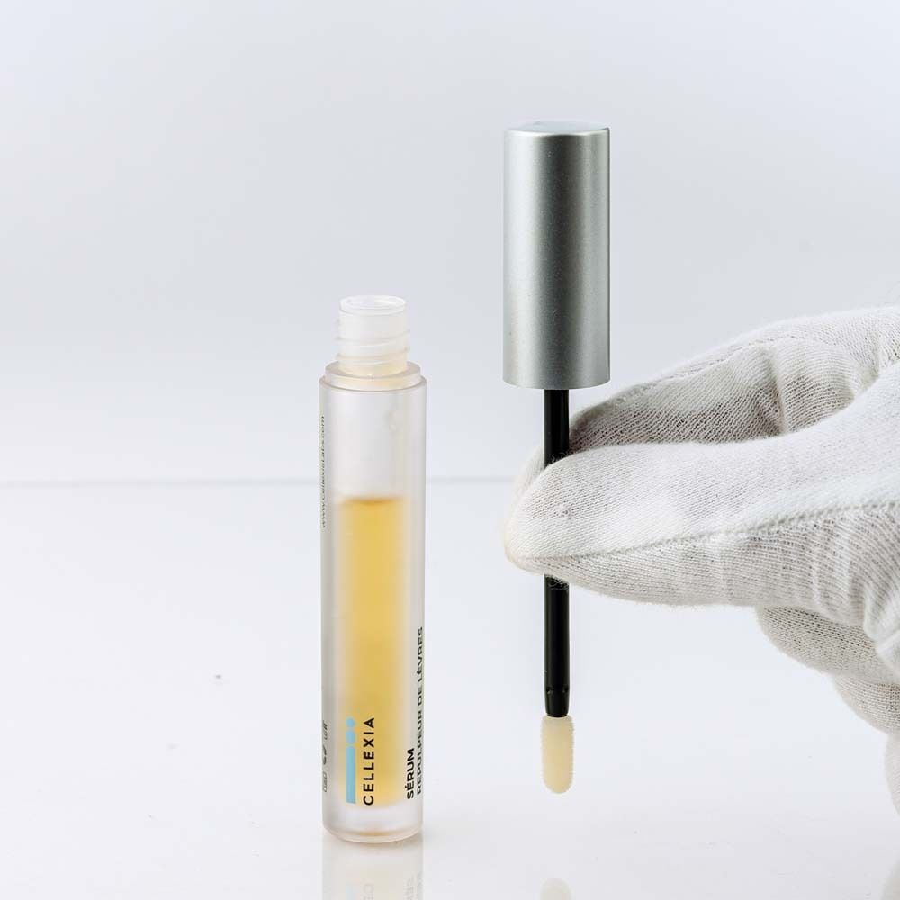 Fläschchen mit Serum und Applikator, gehalten von einer Hand mit weißem Handschuh.