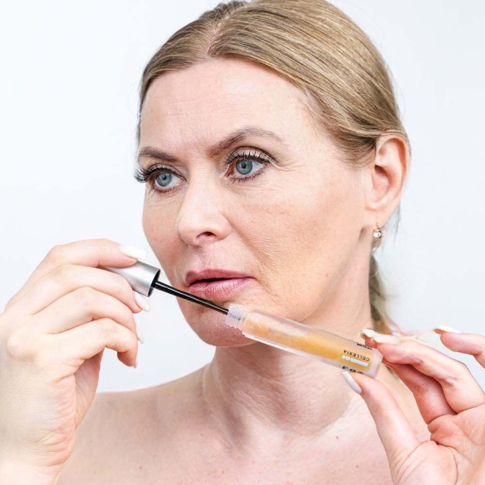 Frau hält Fläschchen und Applikator an ihre Lippen. Produkt sichtbar.