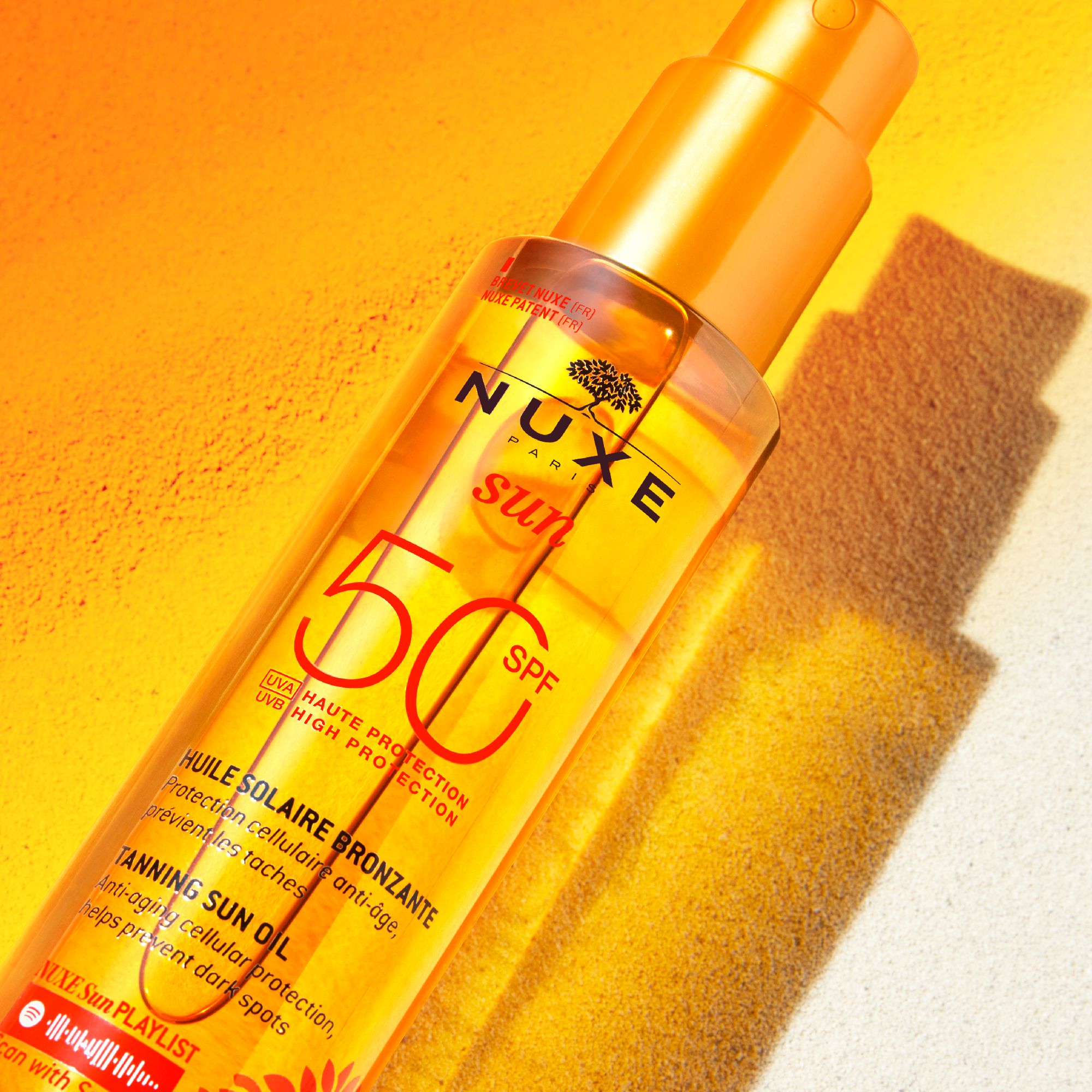 NUXE Sun Ölflasche mit SPF 50. Orangefarbener Hintergrund. Produktetikett mit Text.