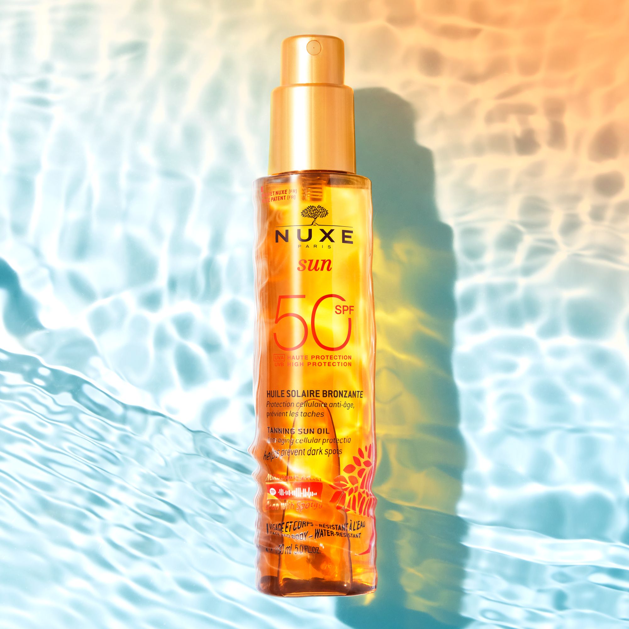 NUXE Sun Ölflasche mit SPF 50. Produkt im Wasser. Orangefarbenes Etikett.