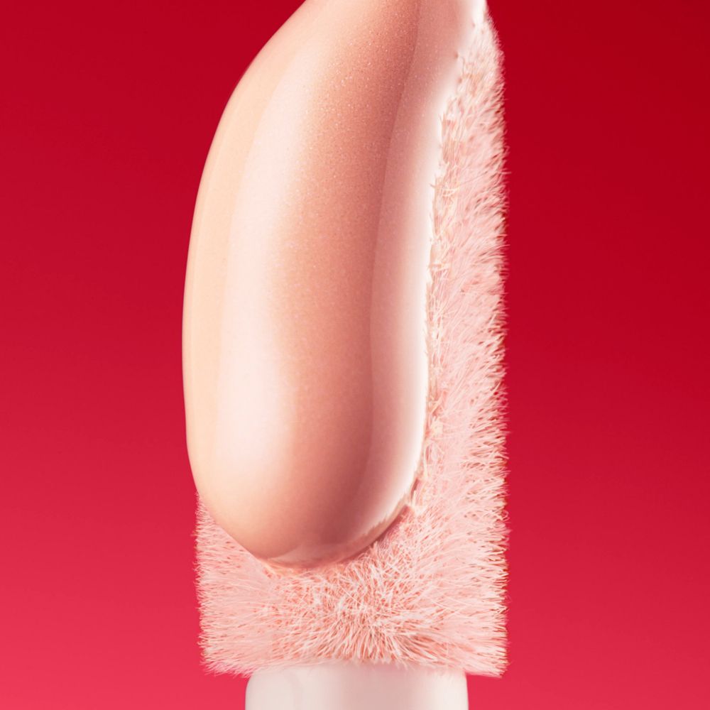 Applikator mit Serum. Rosa getönte Flüssigkeit. Borsten am Ende des Applikators.