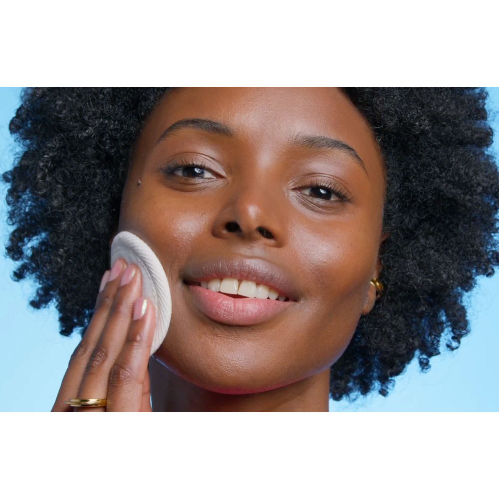 Gros plan d'une femme nettoyant son visage avec un coton. Peau claire, bague au doigt.