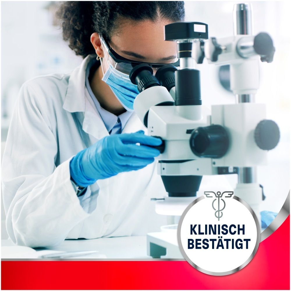 Wissenschaftlerin mit Schutzbrille und Maske blickt durch ein Mikroskop. "Klinisch bestätigt" Siegel.