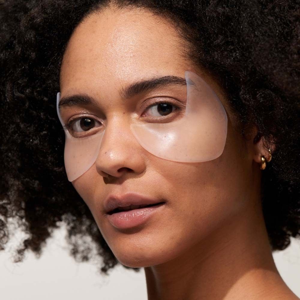 Eine Frau mit zwei Augen-Schläfen Pads auf der Haut. Pads sind transparent und bedecken die Augenpartie und Schläfen.