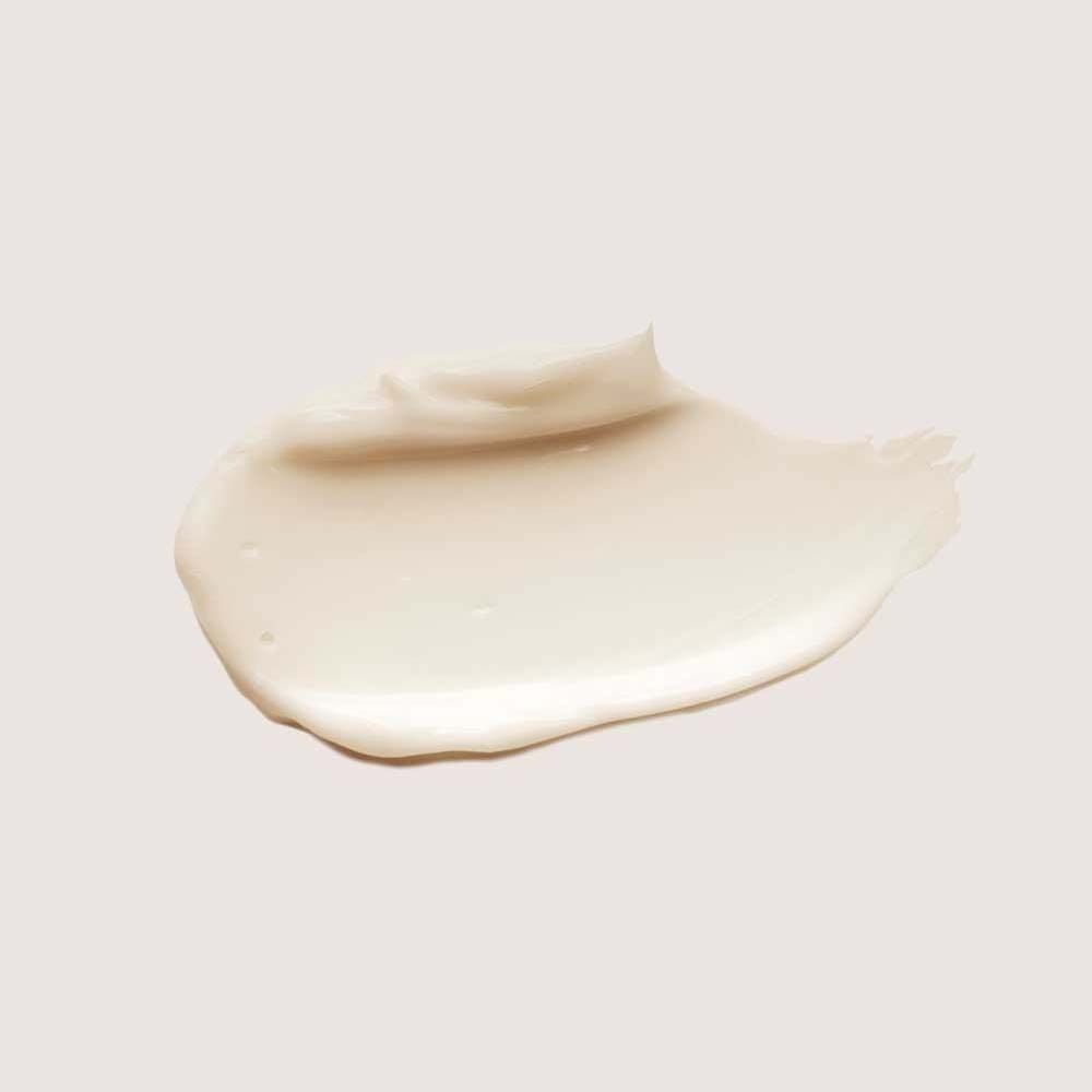 Éclaboussure d'un soin capillaire crème sur fond clair. Texture lisse.