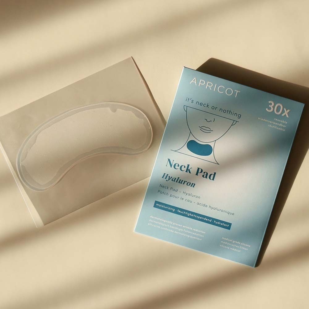 Verpackung und Neck Pad. Verpackung: APRICOT Neck Pad mit Hyaluron. Ein Pad liegt daneben.