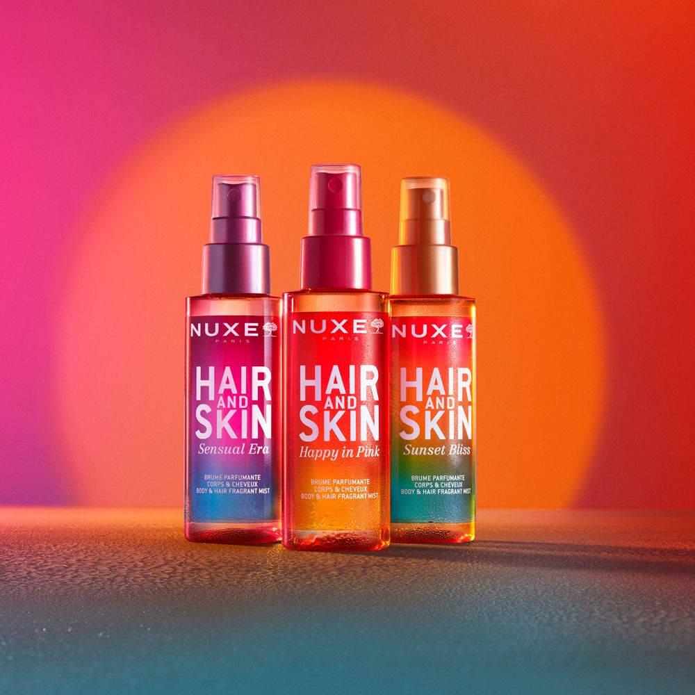 Drei NUXE® Hair and Skin Duftsprays. Sensual Era, Happy in Pink, Sunset Bliss. Farbverlauf-Hintergrund.
