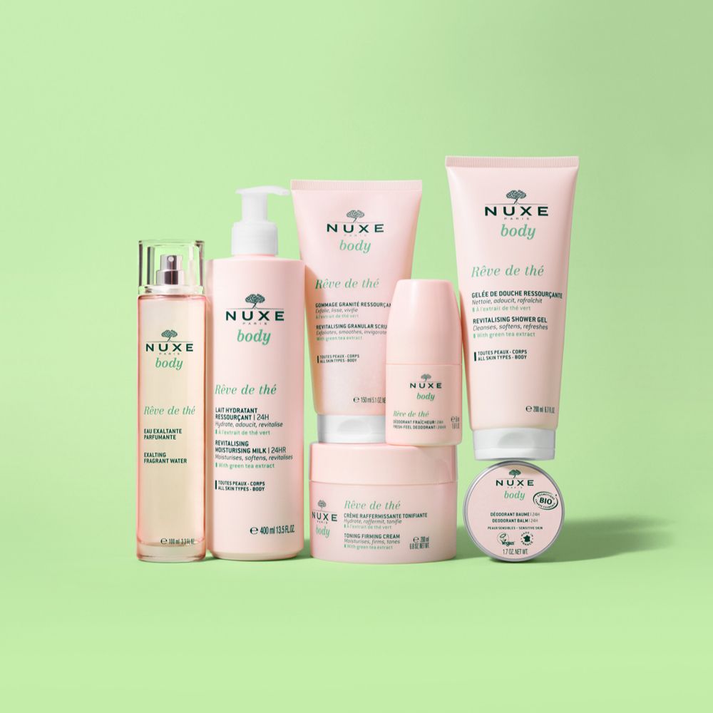 Verschiedene NUXE Rêve de thé Produkte. Sprühflasche, Lotion, Deodorant, Creme, Duschgel. Rosa und grüne Verpackung.