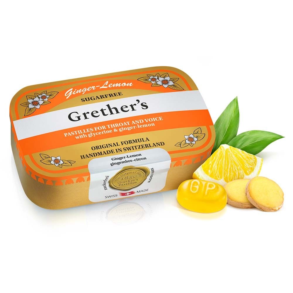 Boîte dorée Grether's Pastilles Ginger Lemon. Citron, gingembre et pastilles à côté. Label de qualité suisse.