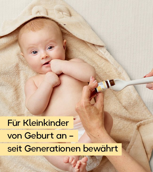 Baby erhält Tropfen aus einem Löffel, der von einer Hand gehalten wird. Brauner Tropfflaschenanhänger mit Etikett.