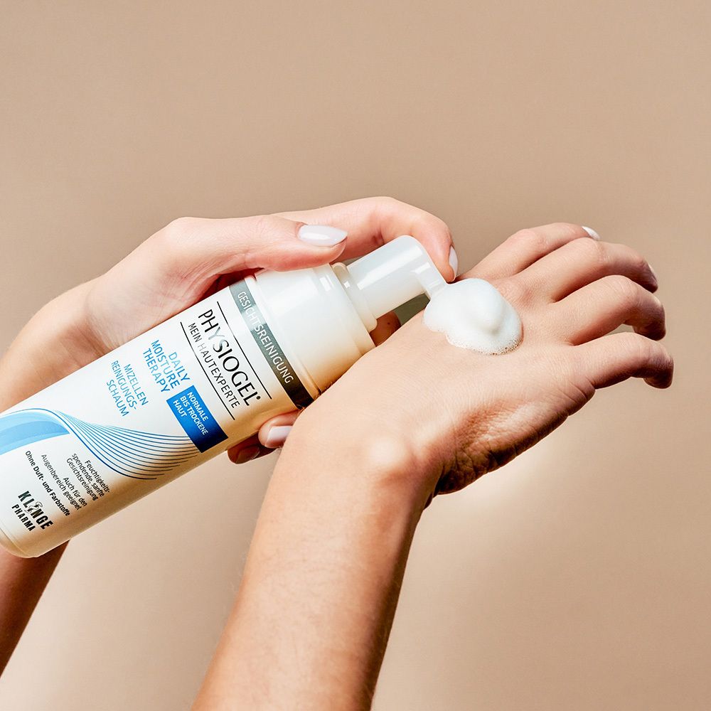 Main pressant la mousse nettoyante PHYSIOGEL® hors du flacon.