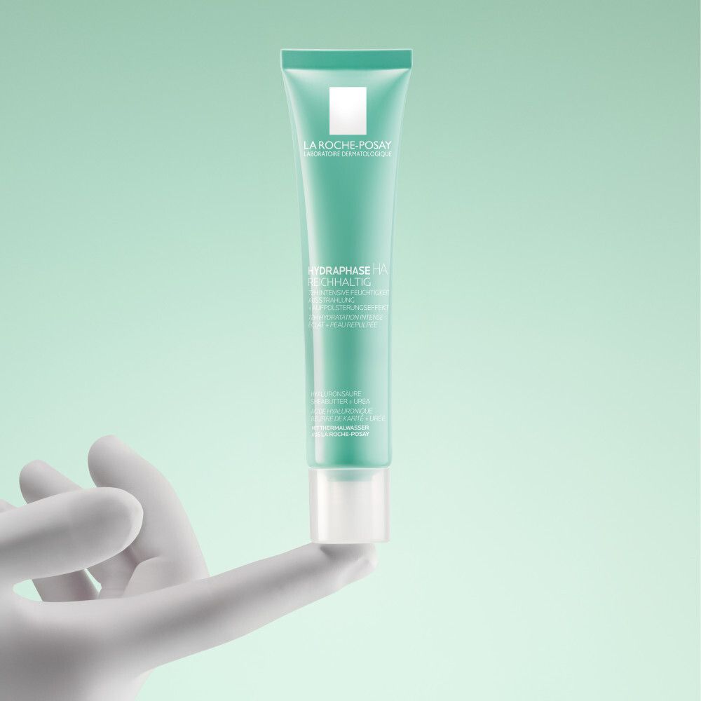 Tube vert dans une main blanche. Inscription: La Roche-Posay, Hydraphase HA Reichhaltig.