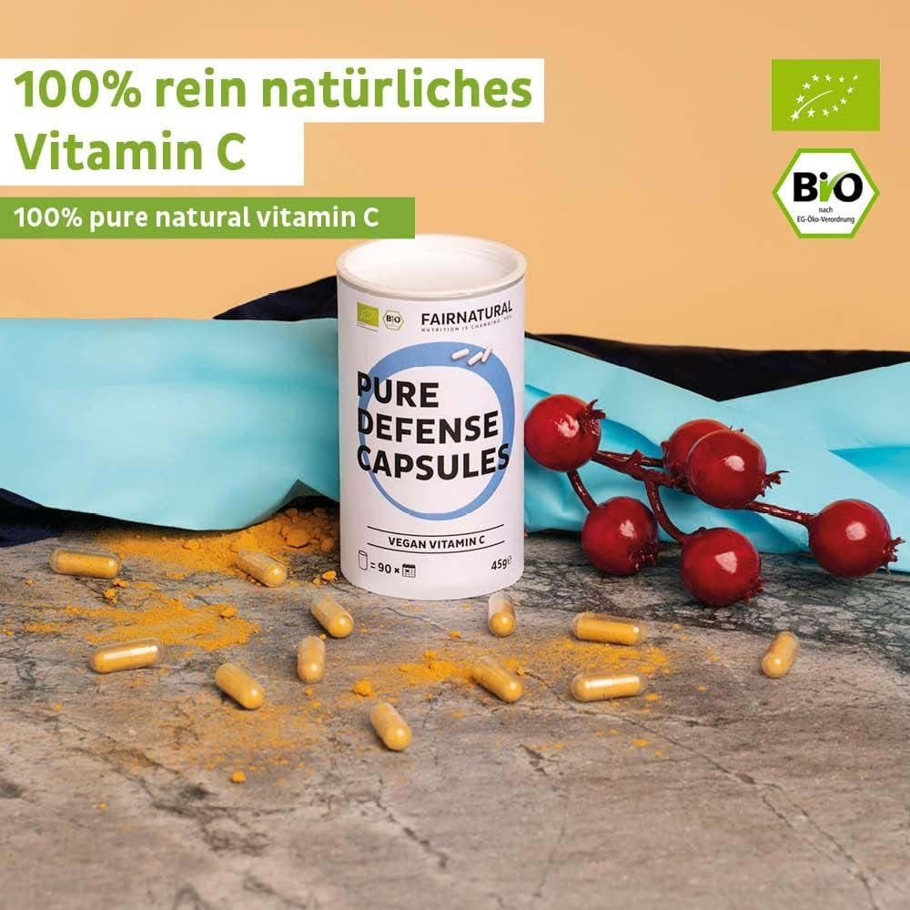 Emballage du produit avec gélules et fruits. Boîte avec inscription : Pure Defense Capsules, Vegan Vitamin C. Label bio. Fond jaune.