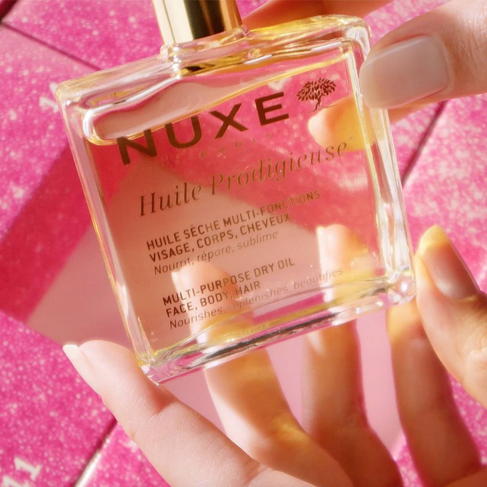 Une main tient une bouteille d'Huile Prodigieuse Multi-Purpose Dry Oil de Nuxe.