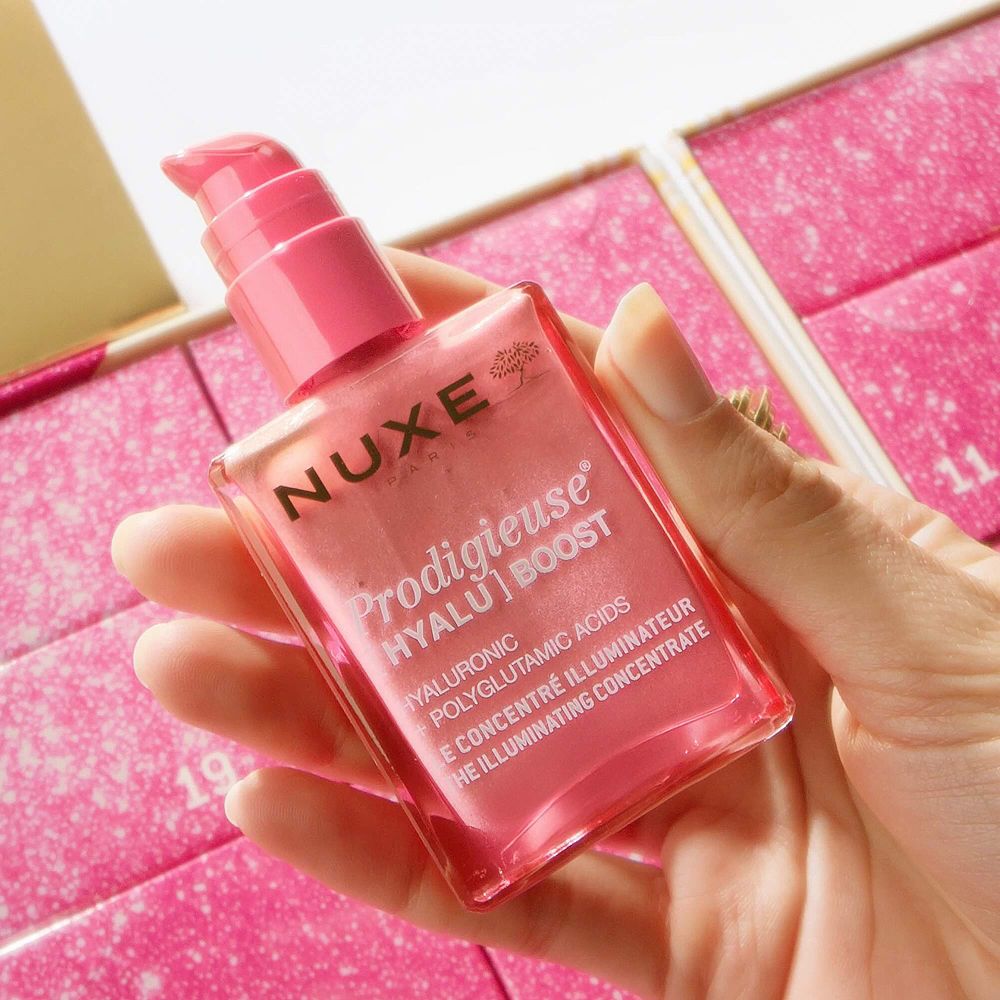 Une main tient une bouteille de Nuxe Prodigieuse Hyalu [Boost] Illuminating Concentrate.