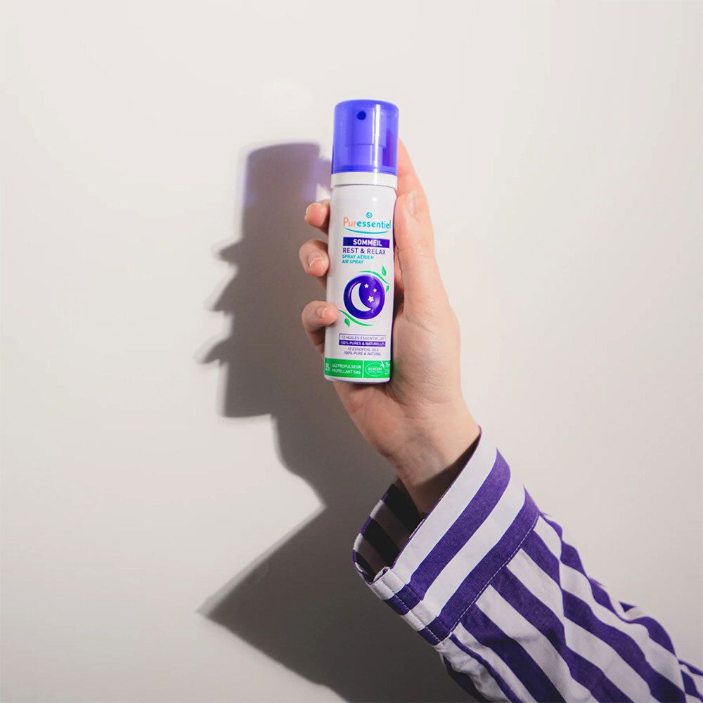 Person hält eine Sprayflasche mit lila Verschluss. Text: Sommeil Rest & Relax. Mond- und Sternen-Logo.
