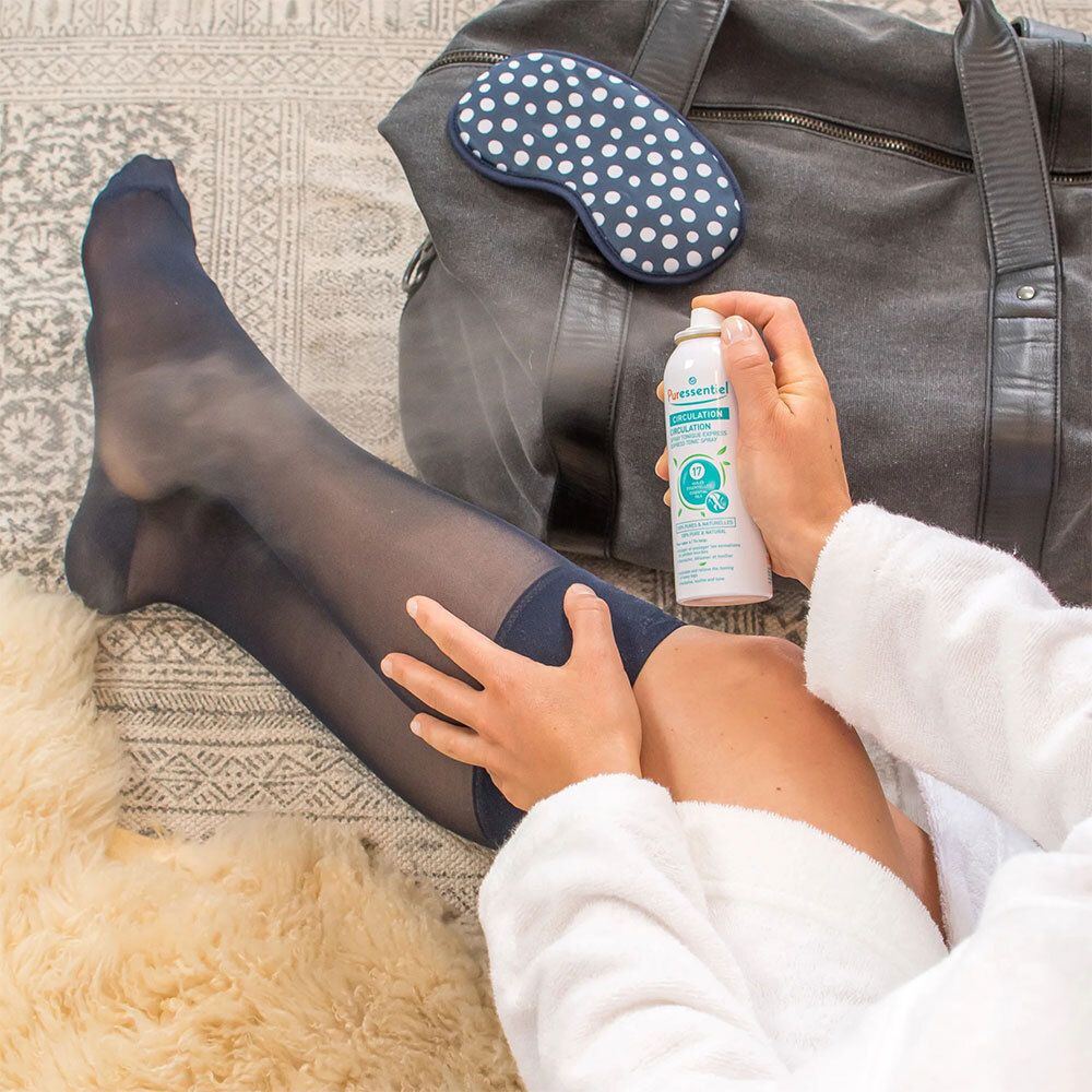 Personne vaporisant un spray blanc avec tête bleue. Inscription: Puressentiel Circulation. 17 huiles essentielles. Sur lit.