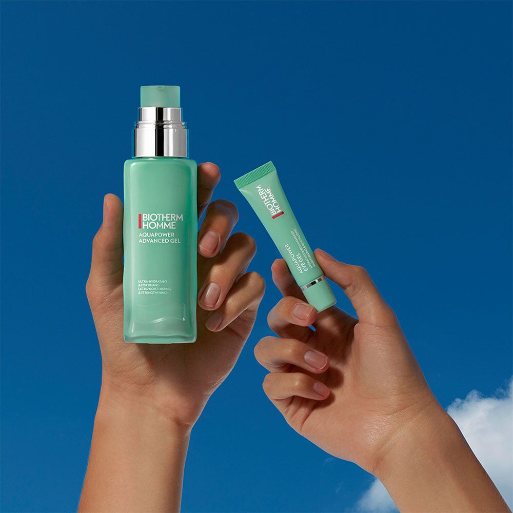 Mains tenant une bouteille et un tube. Bouteille : BIOTHERM HOMME, AQUAPOWER. Tube : BIOTHERM HOMME, AQUAPOWER EYE GEL. Ciel bleu en arrière-plan.