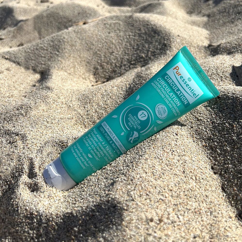 Türkisfarbene Tube im Sand. Aufschrift: Puressentiel Circulation. Enthält 17 ätherische Öle. Sans Alcool.