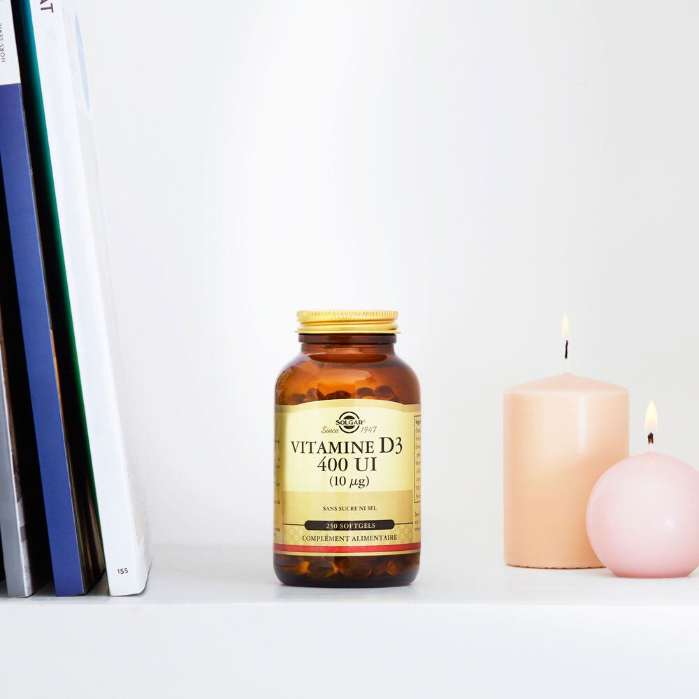 Braune Flasche mit goldenem Deckel auf einem Regal. Daneben Kerzen und Bücher.