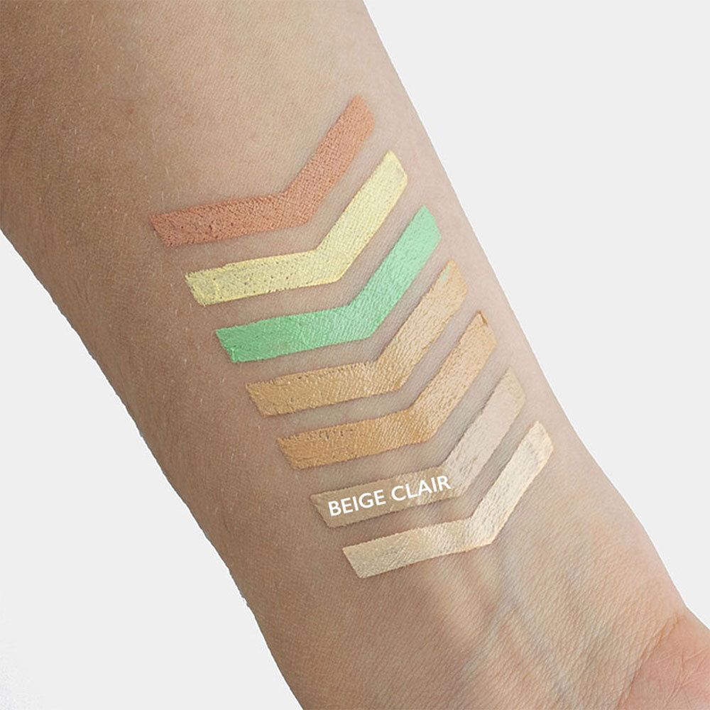 Arm mit sechs Farbproben von Concealern. Farben: Orange, Gelb, Grün, Beige, Hellbeige und Weiß.