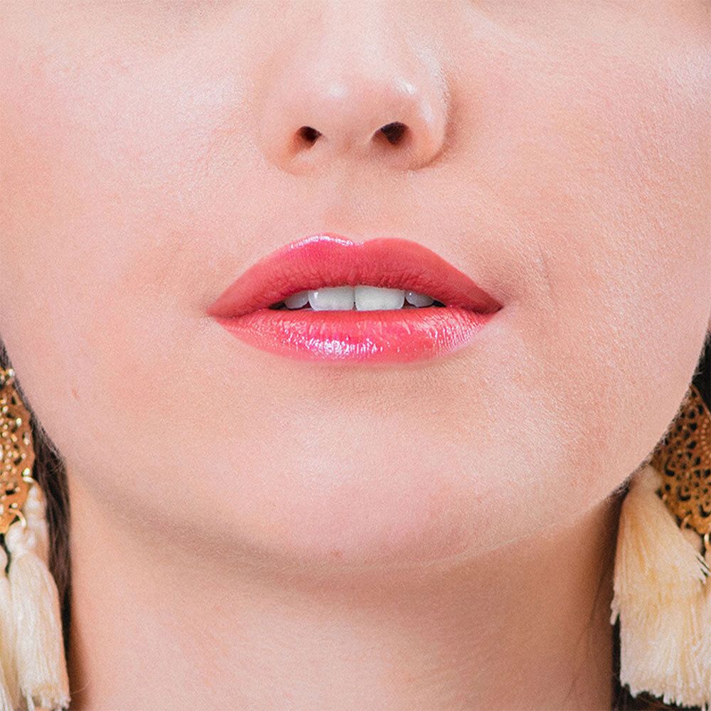 Nahaufnahme von Lippen mit rosafarbenem Lippenstift. Hautton, goldene Ohrringe.