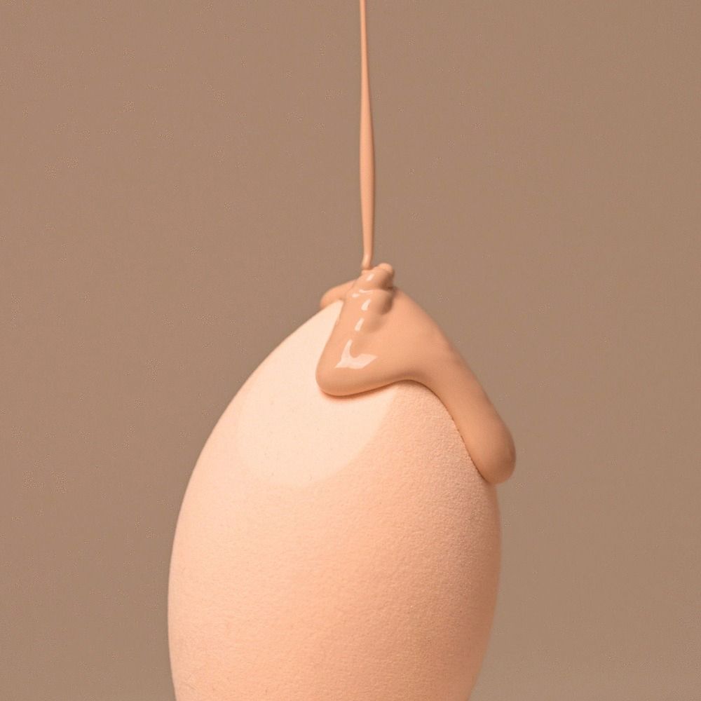 Beigefarbener Make-up-Schwamm, Tropfenform. Flüssiges Make-up wird auf die Oberfläche gegossen.