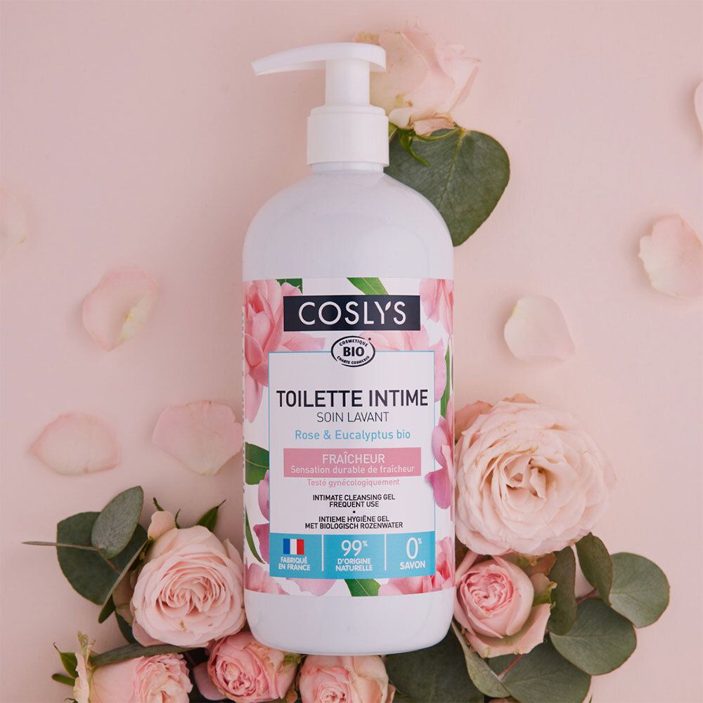 Weißer Spender mit rosa Blüten und Blättern. "Coslys" und "Toilette Intime" sichtbar. Auf rosa Untergrund.