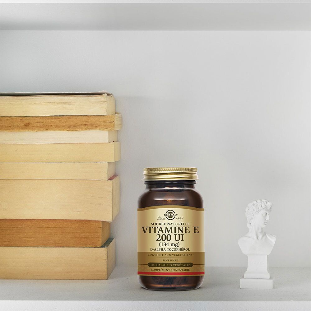 Flacon de vitamine E sur une étagère. Livres et buste en arrière-plan.