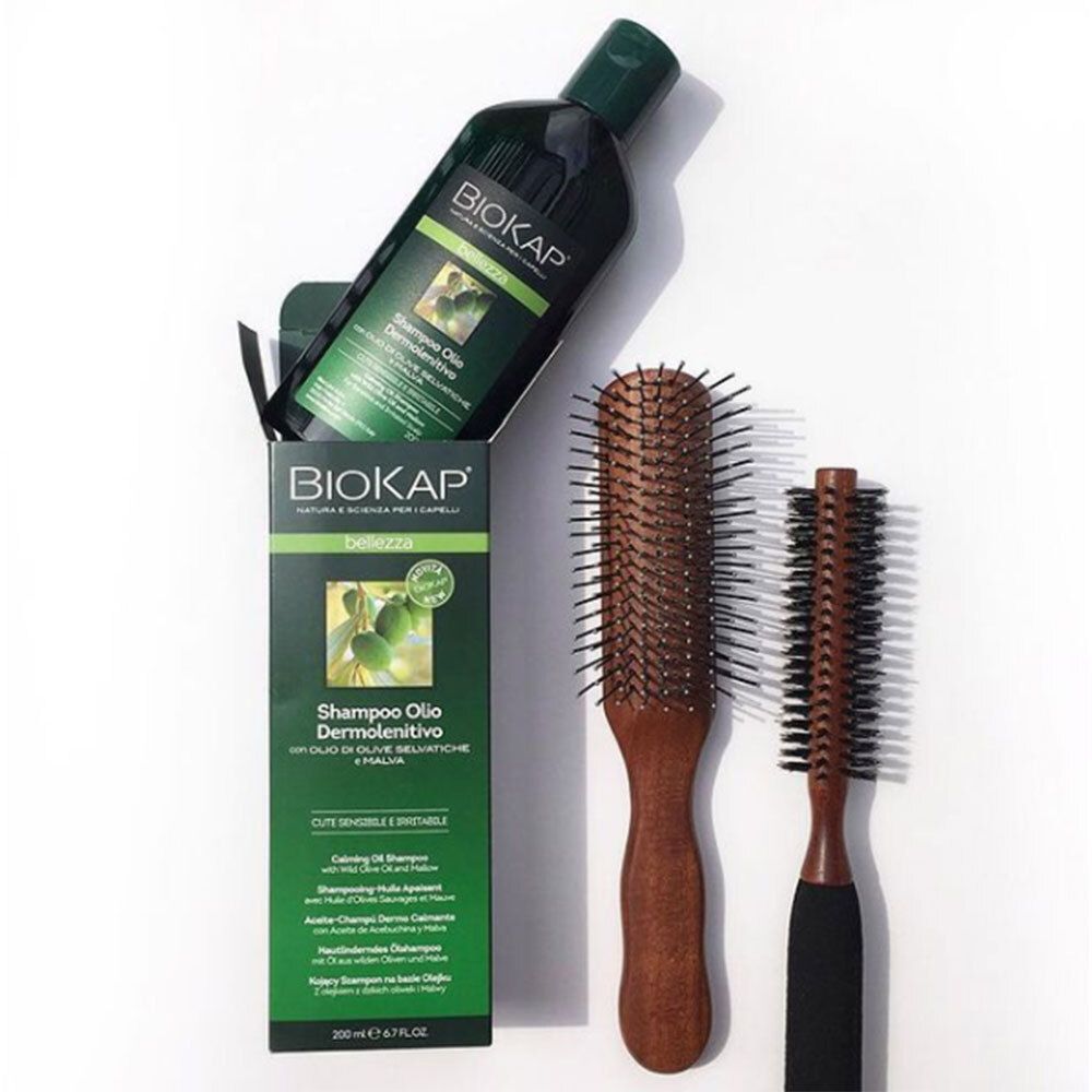 BIOKAP Shampoo-Flasche und Verpackung mit zwei Holzbürsten. Produktname und Marke deutlich sichtbar.