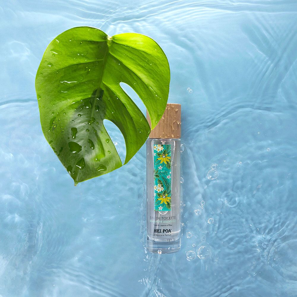 Flacon Eau de Toilette dans l'eau. Feuille à côté. Liquide transparent, bouchon en bois. Fond : eau bleue.