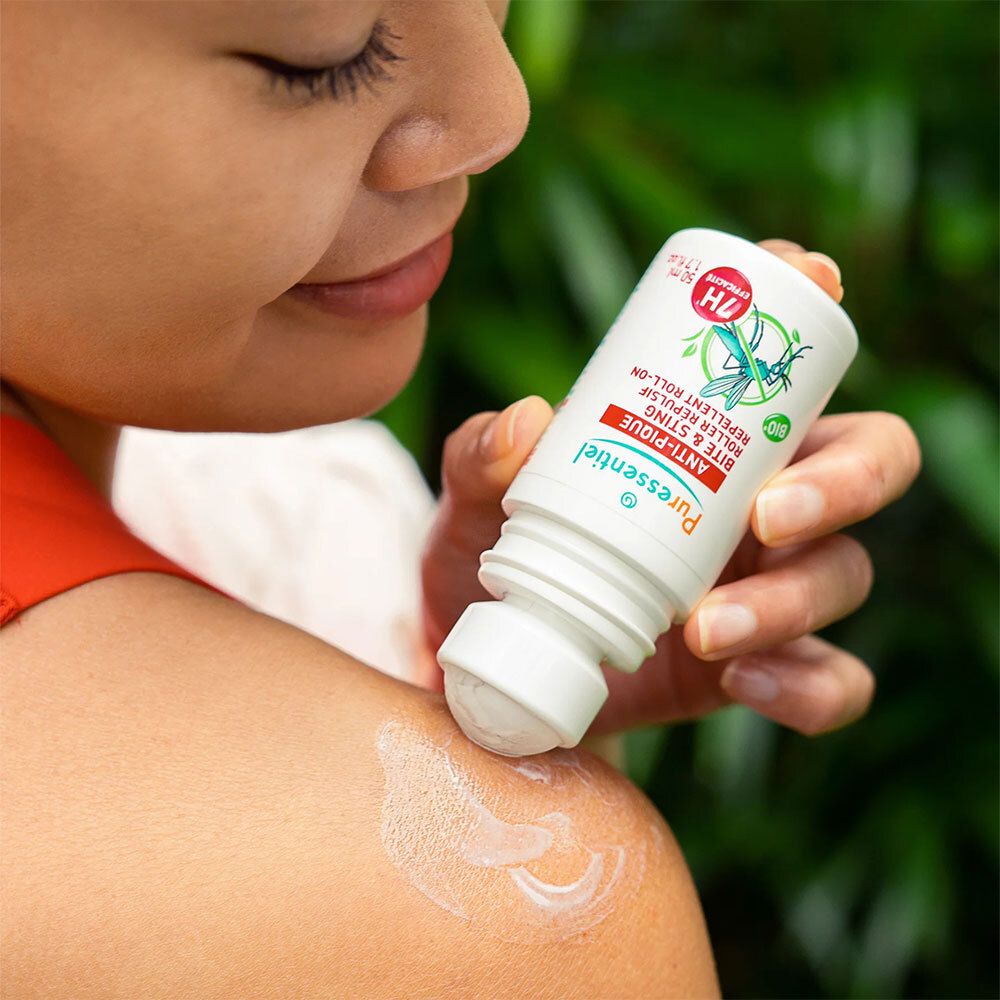 Personne appliquant le roll-on Anti-Pique Puressentiel sur l'épaule. Flacon blanc, bouchon rouge.