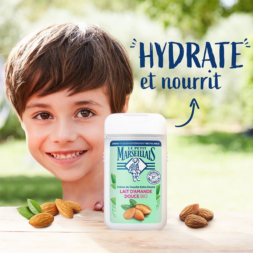 Kind mit Duschgel-Flasche. Text: Hydrate et nourrit. Marke: Le Petit Marseillais. Aufschrift: Lait d'Amande Douce Bio. Mandeln.