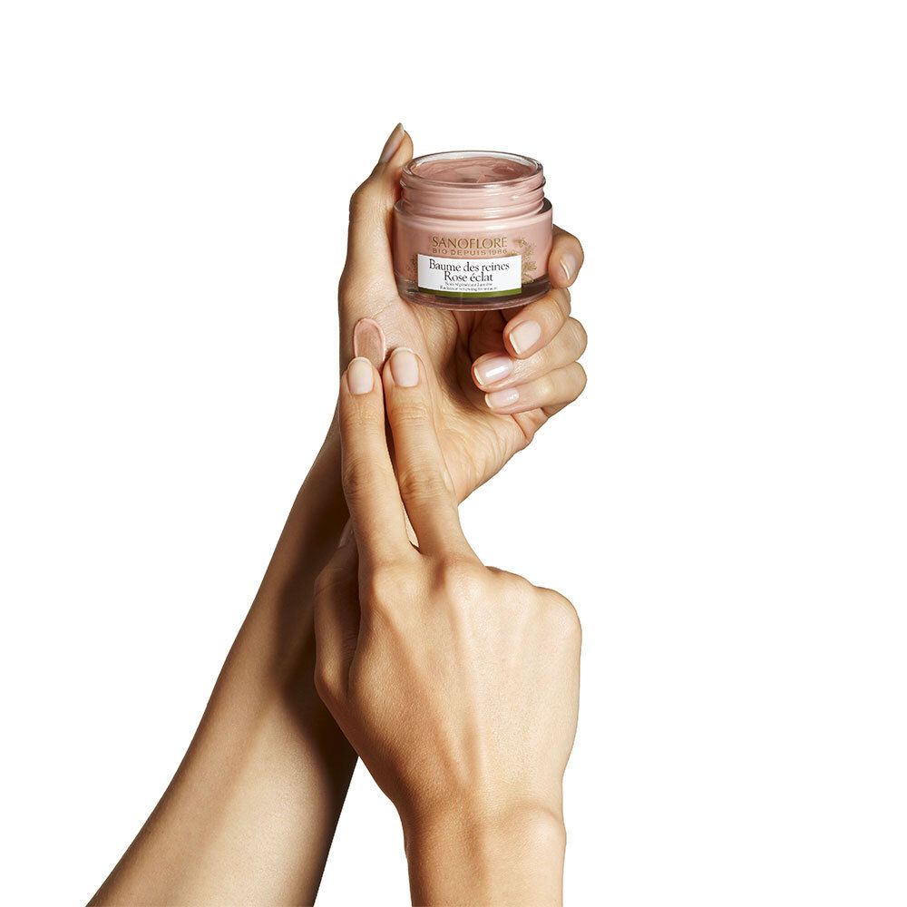 Hände halten Creme-Glas. SANOFLORE, Baume des reines Rose éclat. Rosa Creme. Bio-Zertifizierung.