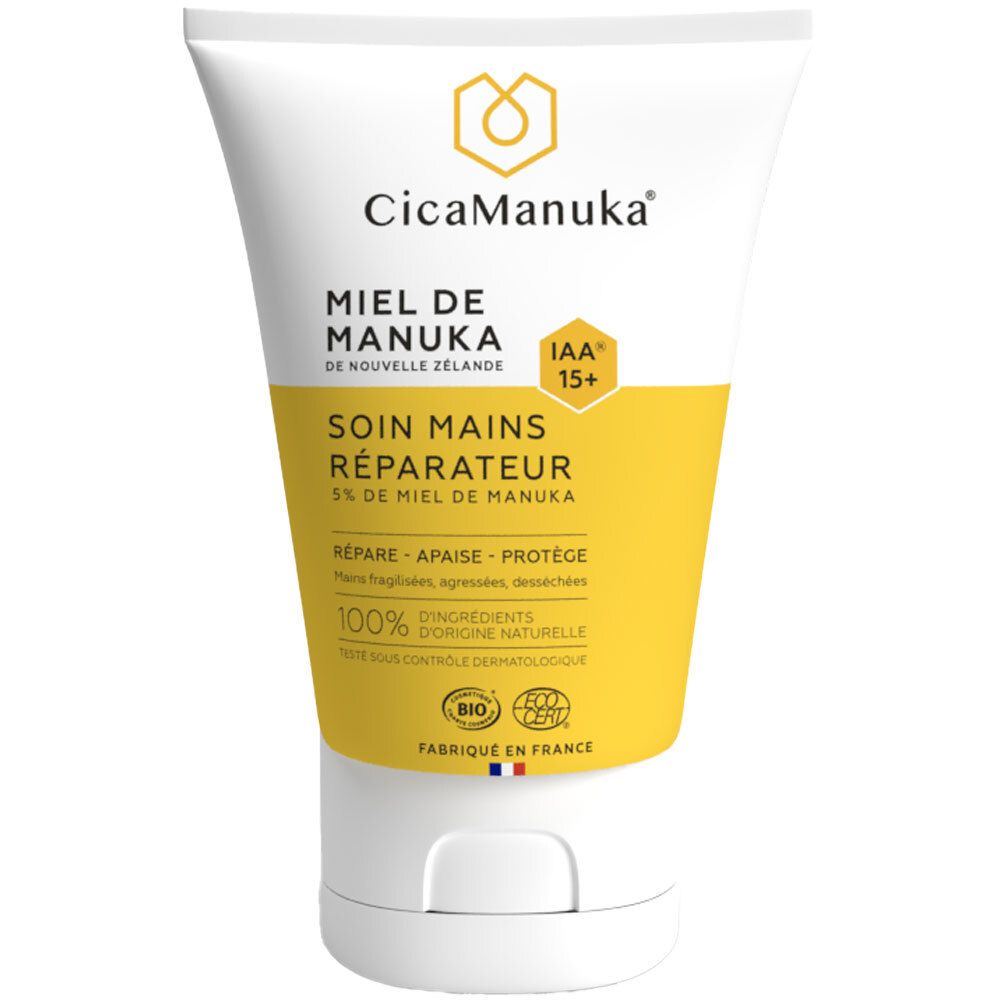 Weiße Tube mit gelbem Etikett. Aufschrift: CicaManuka, Miel de Manuka, Soin mains réparateur. IAA15+ Zertifizierung.
