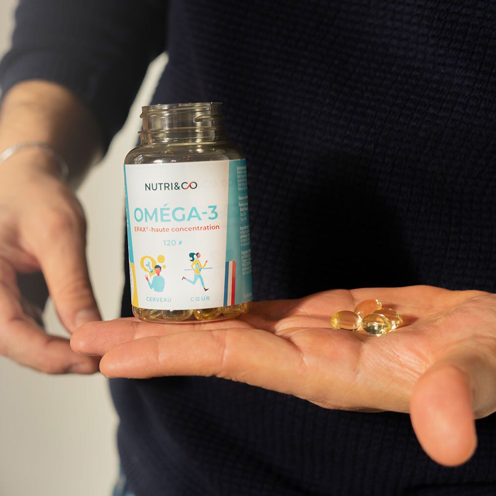 Main tenant flacon et capsules. Inscription: NUTRI&CO Oméga-3 EPAX. Capsules jaunes et transparentes.