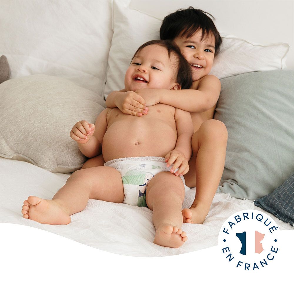 Deux bébés avec des couches. Inscription: Fabriqué en France. Couche avec illustration d'un toucan.