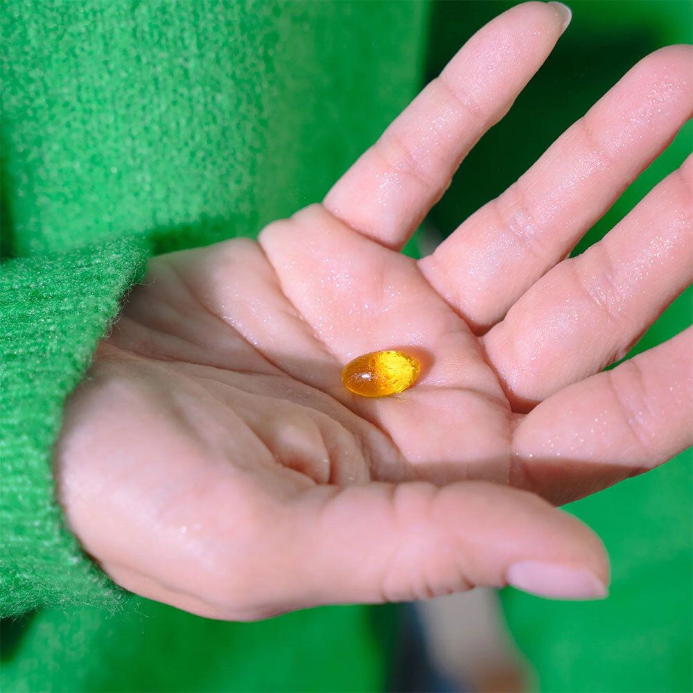 Capsule jaune dans une main. Pas d'emballage visible.
