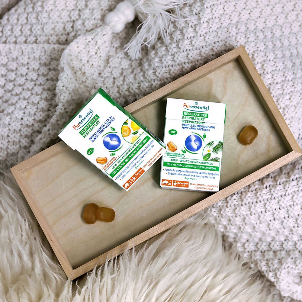 Zwei Packungen mit Pastillen auf einem Holztablett. Gelbe Pastillen daneben. Aufschrift: RESPIRATOIRE.