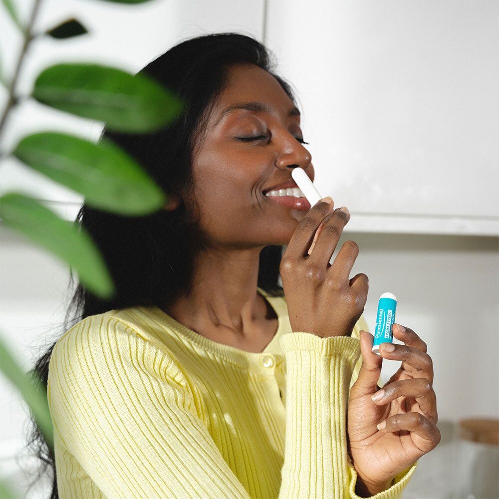 Eine Frau benutzt einen Puressentiel AROMA STRESS® Inhalator. Aufschrift: AROMA STRESS® Inhaler/Inhalator.