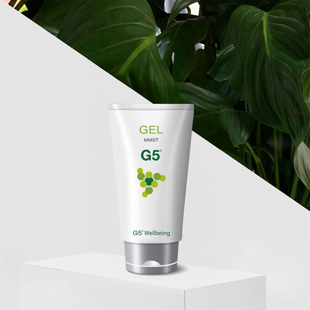 Weiße Tube mit Aufschrift: GEL MMST G5. Logo: grüne Kreise. Silberner Verschluss. Vor Pflanzen.