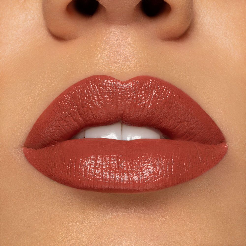 Nahaufnahme von Lippen, bedeckt mit semi-mattem, pfirsichfarbenem Lippenstift. Hautton sichtbar. Glänzendes Finish.