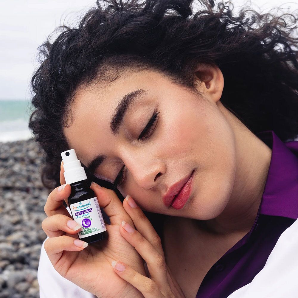 Frau hält eine braune Glasflasche mit weißem Sprühkopf. Aufschrift: PURESSENTIEL Sommeil Spray bukkal.