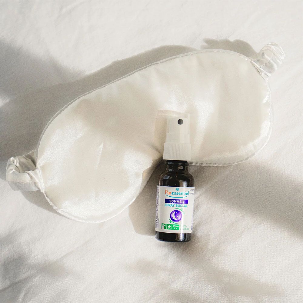 Braune Glasflasche mit weißem Sprühkopf und Augenmaske auf weißer Oberfläche. Aufschrift: PURESSENTIEL Sommeil Spray bukkal.