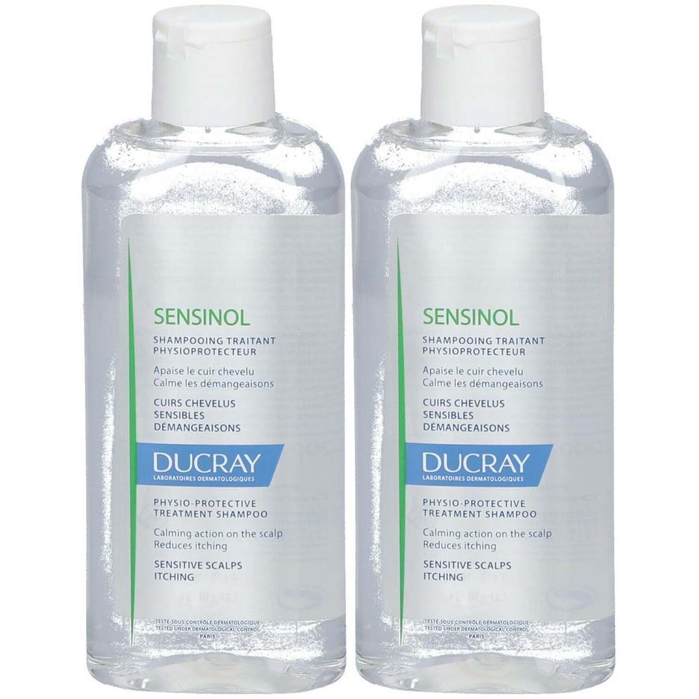 Zwei transparente Flaschen mit weißem Deckel. Auf den Etiketten steht "SENSINOL" und "DUCRAY". Text: "PHYSIO PROTECTIVE TREATMENT SHAMPOO".